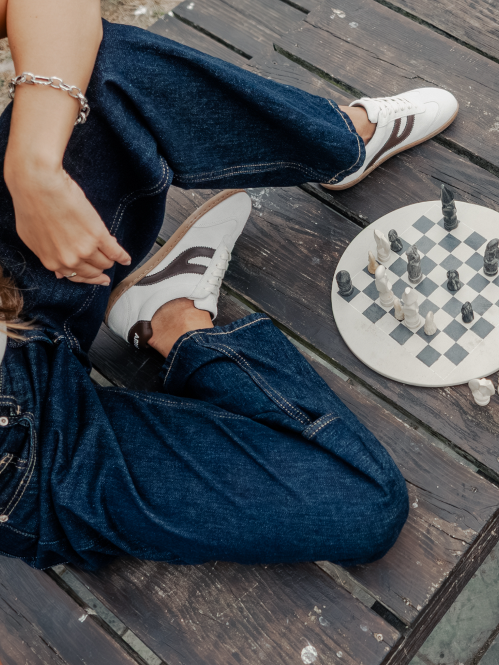Persona sentada en suelo de madera con zapatillas barefoot Atlantic Mist blancas y ajedrez — ARNASA