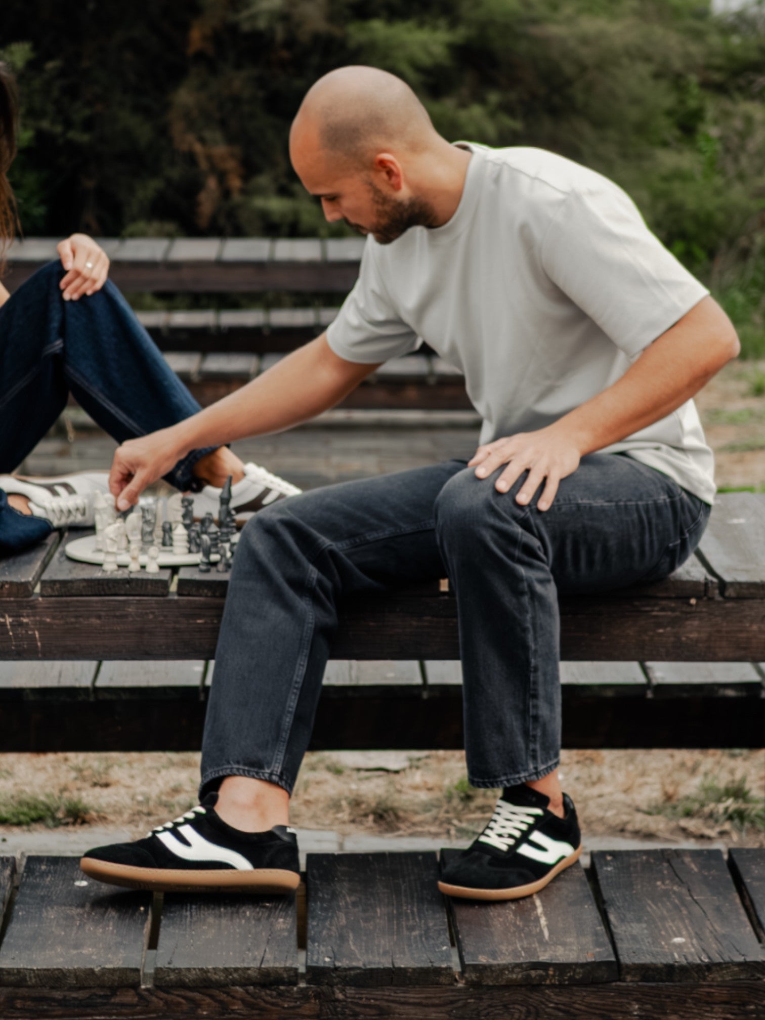 Hombre sentado en banco con zapatillas barefoot Atlantic Coal negras — ARNASA