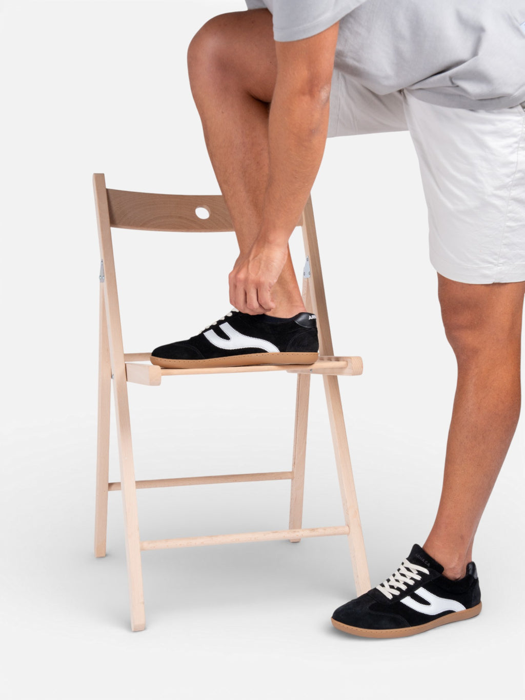 Hombre apoyando pie en silla con zapatillas barefoot Atlantic Coal negras — ARNASA